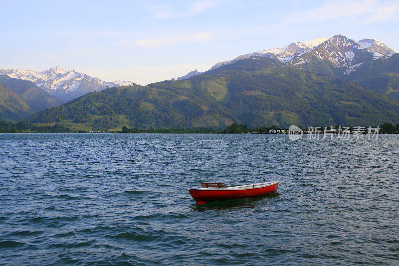 孤独的红船漂浮在美丽的泽勒湖上-泽尔am See和山脉景观，Tirol风景在奥地利萨尔茨堡土地，奥地利